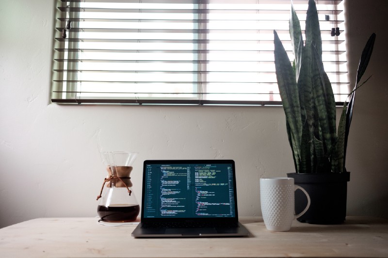 A desk with a open laptop with some code on it